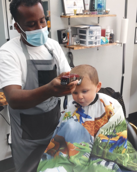E the Barber giving a young client a haircut
